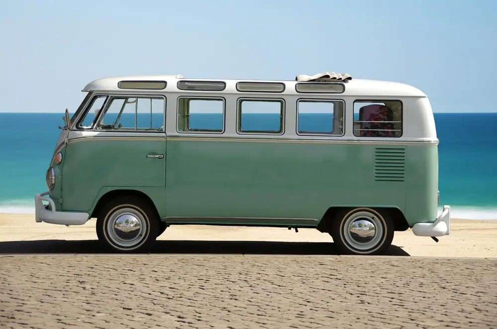 Klassischer grün-weißer Campervan auf einer gepflasterten Fläche am Meer