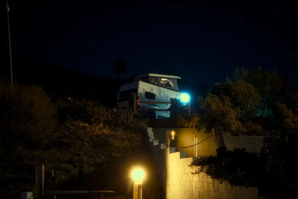 Campervan nachts an einem Hang mit beleuchtetem Weg im Vordergrund