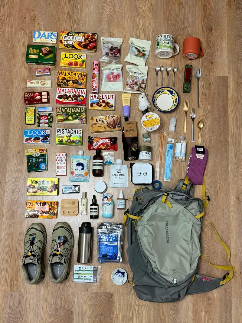 Reiseausrüstung und Snacks auf einem Holzboden neben Rucksack und Schuhen