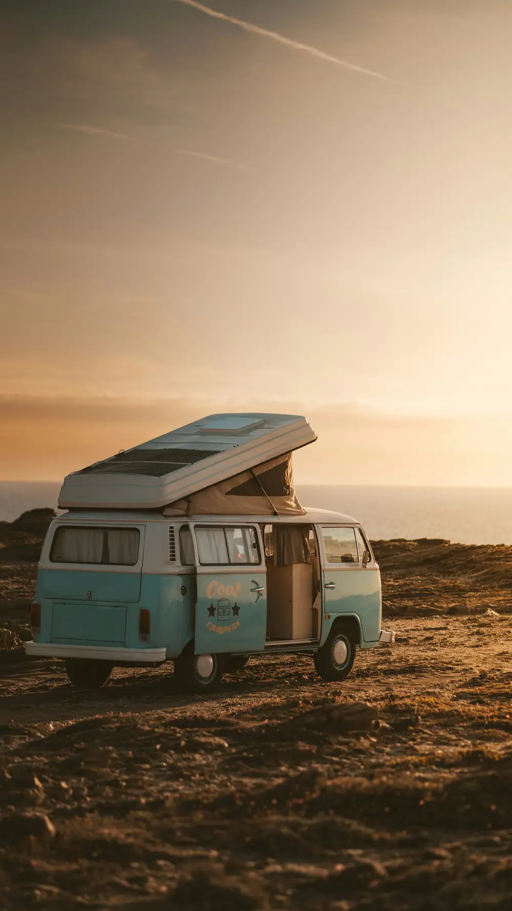 Alter Campervan mit Aufstelldach am Meer im warmen Abendlicht